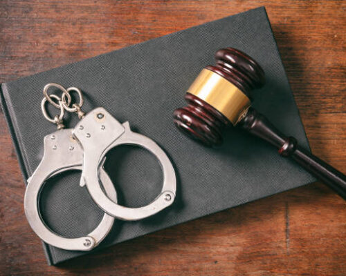 Law and order concept. Handcuffs, gavel on book on a wooden background, top view